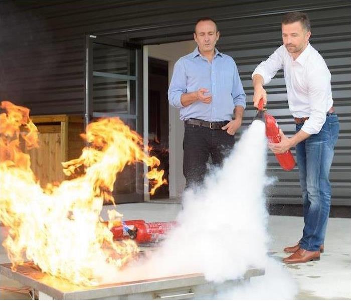 2 men putting out a fire with a fire extinguisher